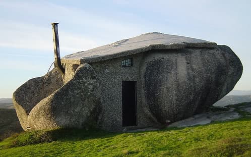 casa de piedra y madera hecha entre grandes rocas